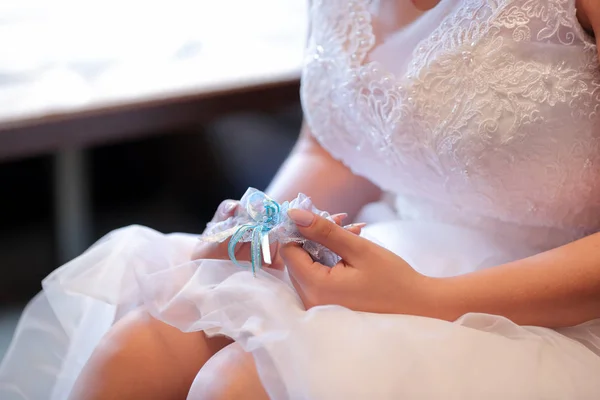 Bruden håller vackra vita och blå bröllop strumpeband — Stockfoto