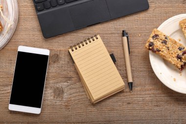 Dizüstü bilgisayar, akıllı telefon ve masanın üstünde defter