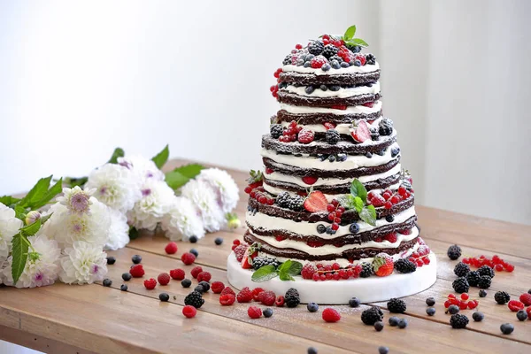 Wedding rustic naked cake with fruits on wooden background