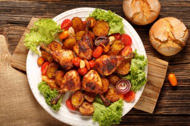 Kızarmış tavuk budu ve tabağında fırında patates.