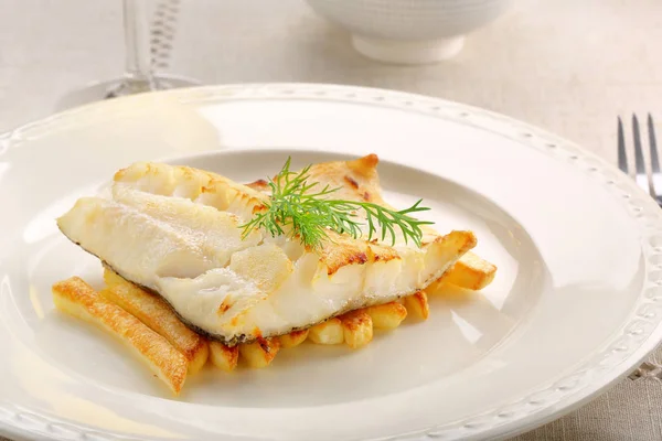 Жареное филе трески на белой тарелке и картофель фри — стоковое фото