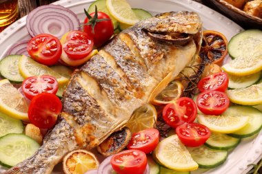 Ahşap arka planda sebzeli kızarmış dorada balığı.