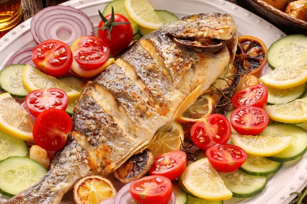 Ahşap arka planda sebzeli kızarmış dorada balığı.