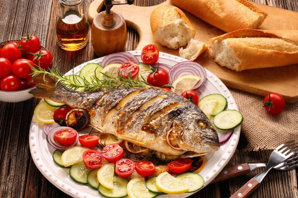 Ahşap arka planda sebzeli kızarmış dorada balığı.