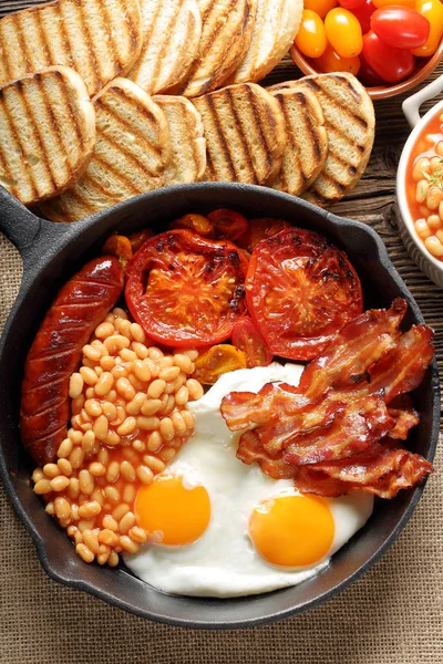 Englisches Frühstück mit Würstchen, gegrillten Tomaten, Ei, Speck und — Stockfoto