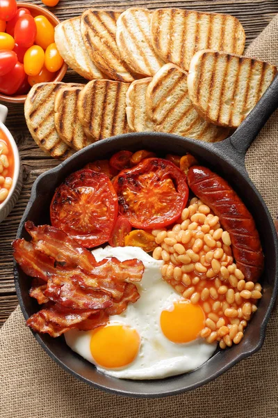 Englisches Frühstück mit Würstchen, gegrillten Tomaten, Ei, Speck und — Stockfoto