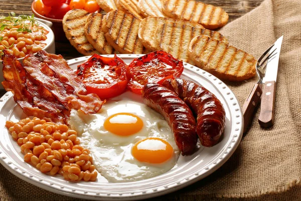 Englisches Frühstück mit Würstchen, gegrillten Tomaten, Ei, Speck, — Stockfoto