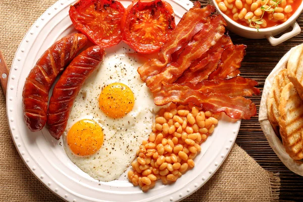 Englisches Frühstück mit Würstchen, gegrillten Tomaten, Ei, Speck, — Stockfoto