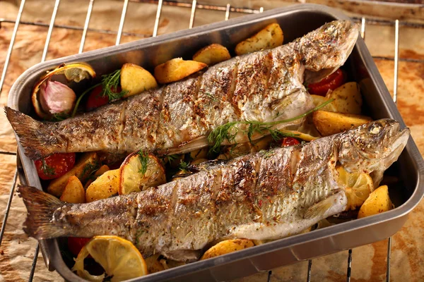 Жареная рыба с картошкой на деревянном фоне — стоковое фото