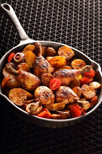 Roasted chicken legs with baked potato on frying pan — Stock Photo, Image