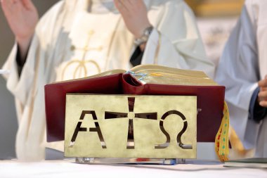 Sunakta Roman Missal ve arka grupta ayini kutlayan rahip.