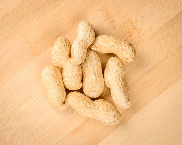 Unpeeled peanuts on wooden cutting board — Stock Photo, Image