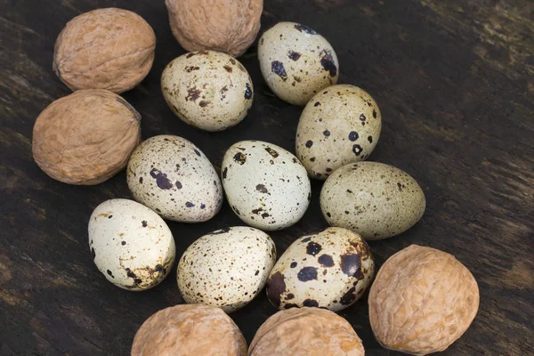 Перепелиные яйца и грецкие орехи на деревянной текстуре как фон — стоковое фото