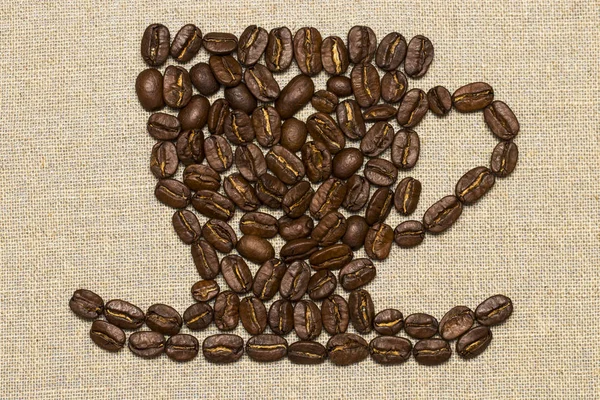 Roasted coffee beans placed in the shape of a cup and saucer on — Stock Photo, Image