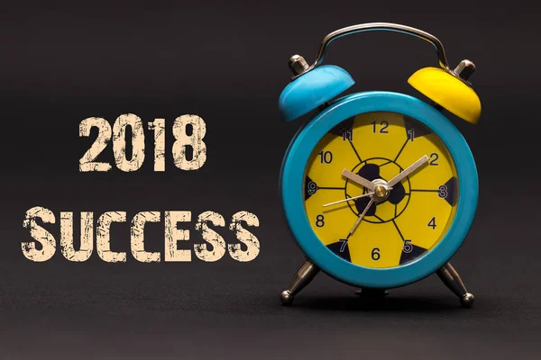 Çalar saat ile siyah kağıt arka plan üzerinde yazılı 2018 başarı
