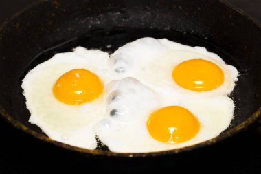 Siyah bir zemin üzerine kahvaltı için bir tavada kızarmış yumurta