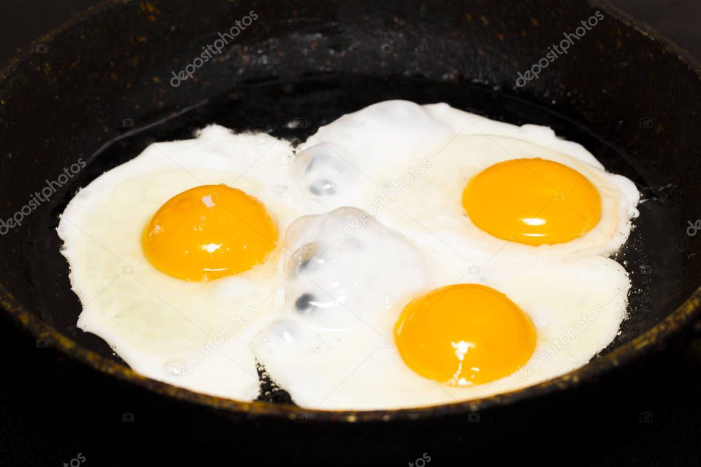 Fried eggs in a frying pan  for breakfast on a black background