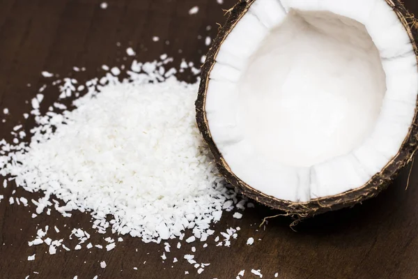 Cocos com flocos de coco isolados no fundo de madeira — Fotografia de Stock