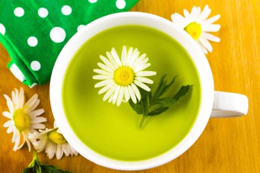 ahşap bir masa üzerinde papatya çiçeği ile bitkisel çay