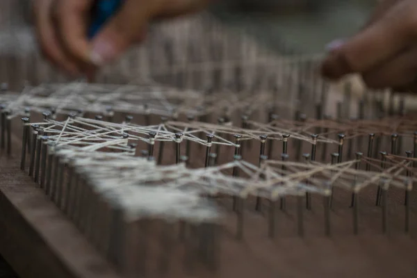 Loose end tied up to wooden board with nails, handcraft textile — Stock Photo, Image