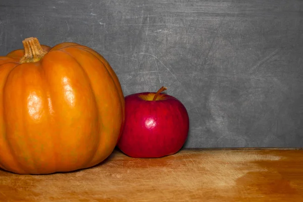 Apfel und Kürbis auf dem Schultisch vor der Tafel — Stockfoto