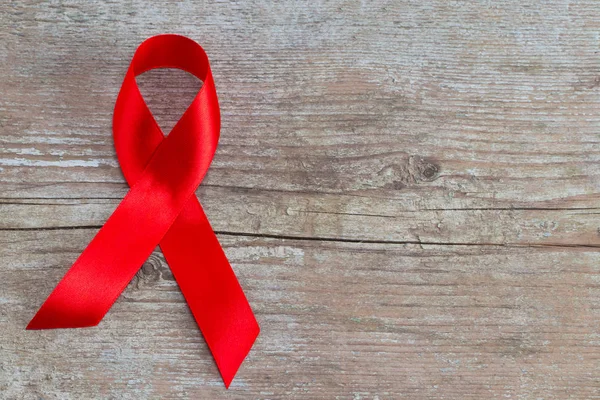 Cinta roja - Símbolo de conciencia sobre el sida en el fondo de madera — Foto de Stock