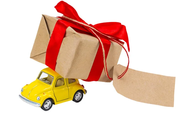 Yellow retro toy car delivering gifts box with tag with empty sp — Stock Photo, Image