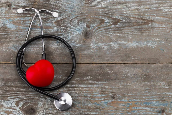 Stethoskop mit rotem Herz auf Holzhintergrund, mit Kopierraum — Stockfoto