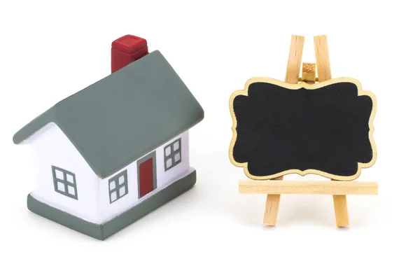 Etiqueta pizarra y modelo en miniatura de casa aislada en blanco — Foto de Stock