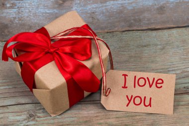 Hediye kutusu ahşap arka plan üzerinde. Kırmızı kurdele. Sevgililer günü g