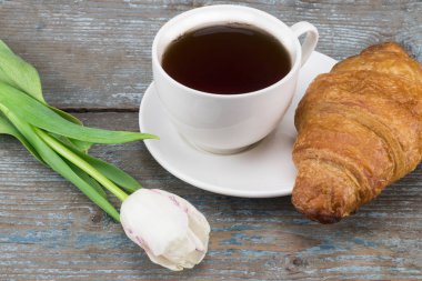 Taze Beyaz Lale ve kahve fincanı ile kruvasan ahşap bac üzerinde