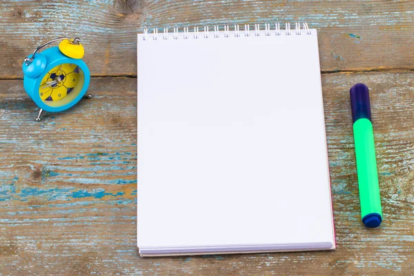 Notebook en wekker op houten achtergrond. Met kopie ruimte — Stockfoto