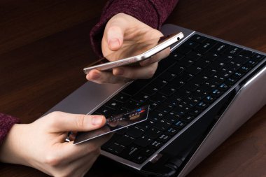 Kredi kartı tutan ve dizüstü bilgisayar kullanan eller. İnternetten alışveriş
