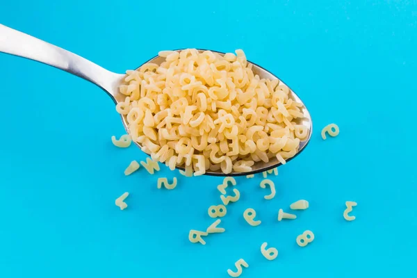 Alphabet pasta in spoon on a blue background — Stock Photo, Image