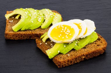 Avokado ve yumurta, siyah taş zemin, üst ile sandviç