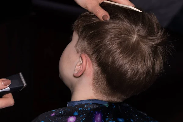 Side view of cute little boy getting haircut by hairdresser at t — Stock Photo, Image