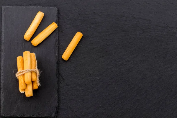 Crispy bread sticks on black stone background with copy space — Stock Photo, Image