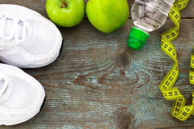 Spor ayakkabı, elma, şişe su ahşap arka plan üzerinde. Konsantrasyon
