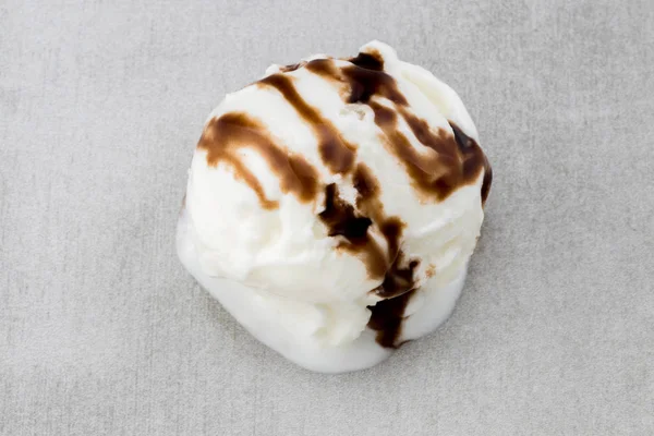 Ice cream ball with chocolate sauce on gray background, top vie — Stock Photo, Image