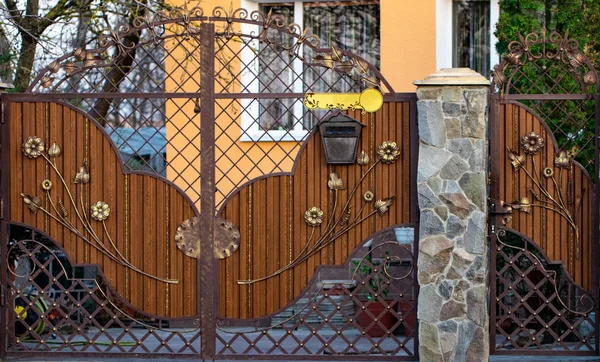 Portão de madeira com belos elementos de ferro forjado flores — Fotografia de Stock