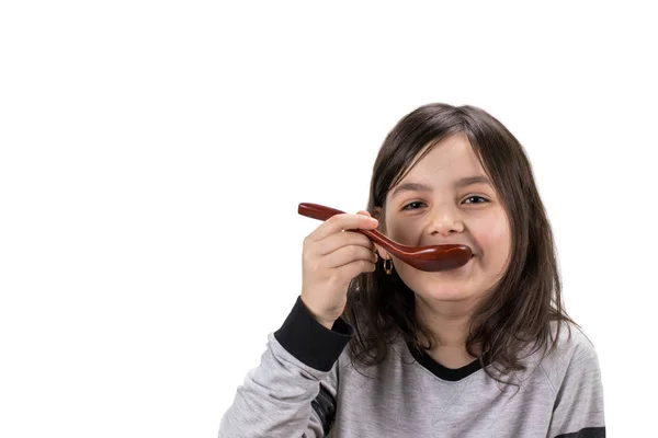 Portrét dívky s dřevěnou lžičkou v ústech, izolované na wh — Stock fotografie