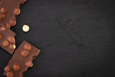 siyah bir arka planda fındık ile sütlü çikolata parçaları. Üst görünüm w