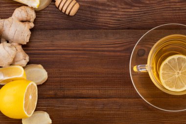 Bir bardak limonlu zencefil çayı, bal ve ahşap üzerinde zencefil kökü. 
