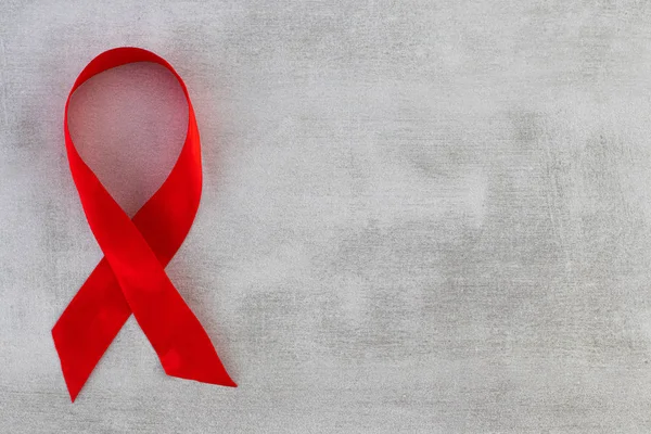Cinta roja - Símbolo de conciencia sobre el sida en el fondo gris con — Foto de Stock