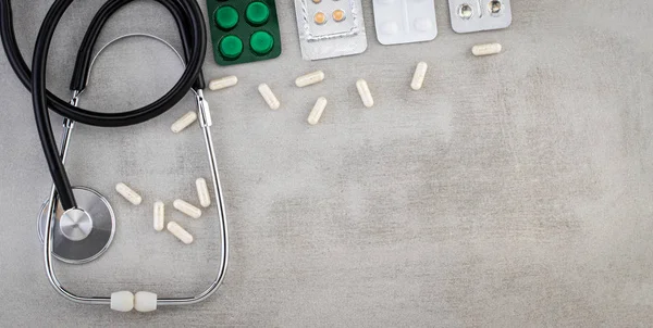Stethoskop, Pillen, Tabletten und Kapseln auf grauem Hintergrund . — Stockfoto