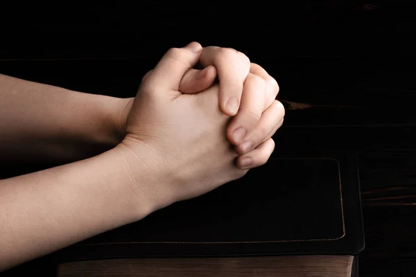 Молящиеся руки в темноте со светом на руках — стоковое фото