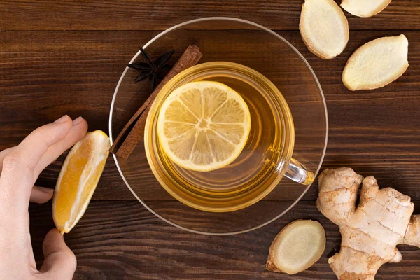 Cup of Ginger tea with lemon, honey and ginger root on a wooden
