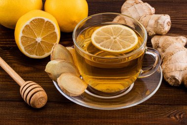 Bir bardak limonlu zencefil çayı, bal ve ahşap üzerinde zencefil kökü. 