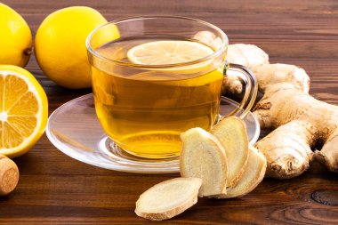 Bir bardak limonlu zencefil çayı, bal ve ahşap üzerinde zencefil kökü. 
