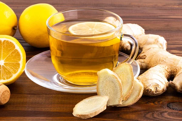 Bir bardak limonlu zencefil çayı, bal ve ahşap üzerinde zencefil kökü. 